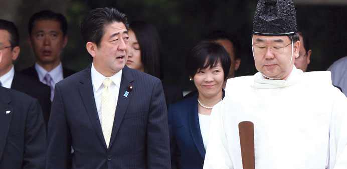 Japanese Prime Minister Shinzo Abe is accompanied by his wife Akie as a Shinto priest leads them during a visit to the Meiji shrine in Tokyo yesterday