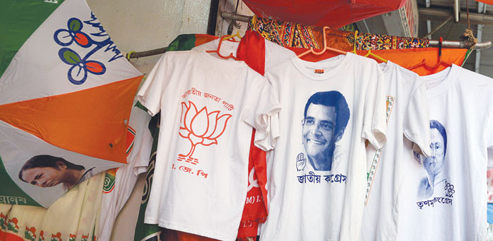 A shopkeeper peeps out from behind merchandise with political symbols at his shop in Kolkata yesterday.