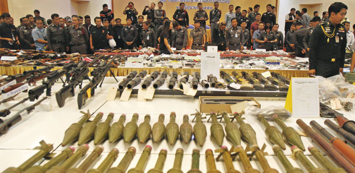 Thai soldiers and police officers look at weapons seized in raids following a military coup on May 22, during a news conference at the military barrac