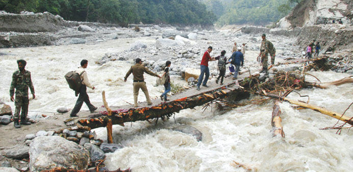 Army personnel help stranded people cross a flooded river after heavy rains in Uttarakhand yesterday.