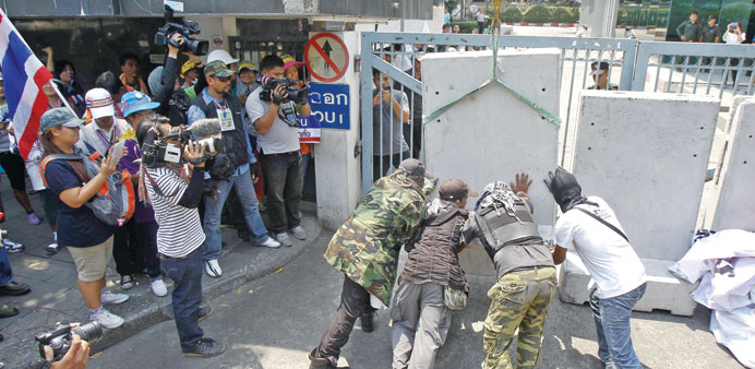 Anti-government protesters set up barricades to block a gate of the Excise Department during a rally in Bangkok yesterday. 