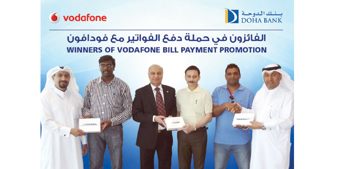 Winners of the Vodafone Qatar utility bill payment promotion with officials.