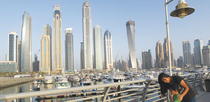 A woman and child stand opposite the Princess Tower (centre) in Dubai. Shares of property firms, the main sector to benefit from a recovery in economi