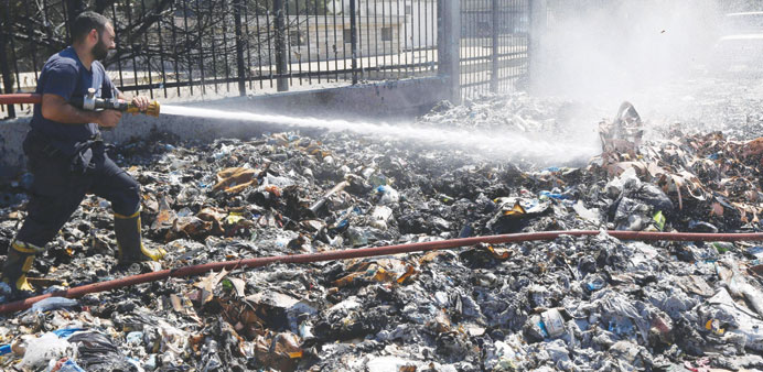 A firefighter sprays water on a pile of garbage that caught fire on a street in Beirut yesterday. 
