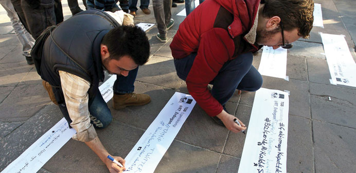People writing slogans during a protest in Ankara on Friday against Erdogan after the government blocked access to Twitter.
