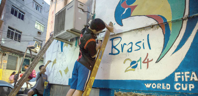 Young men painting a World Cup mural in Rocinha shantytown (favela) in Rio de Janeiro yesterday.