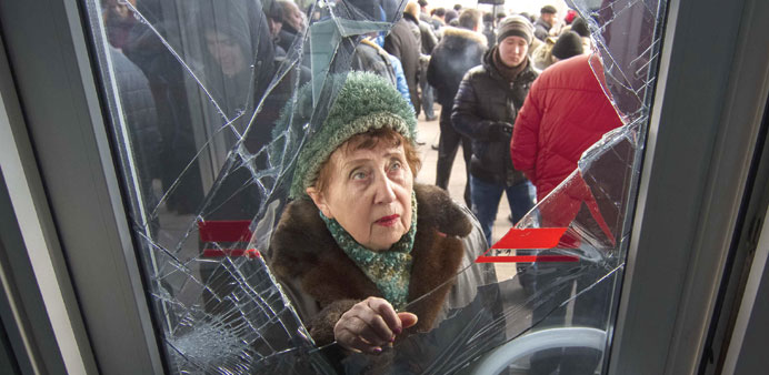 A woman looks through a damaged entrance door as pro-Russian demonstrators hold a rally outside the regional government building in Donetsk.