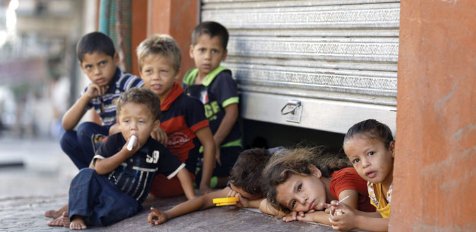 Children peek from under a shop door, where their family is taking shelter, in Gaza City yesterday.