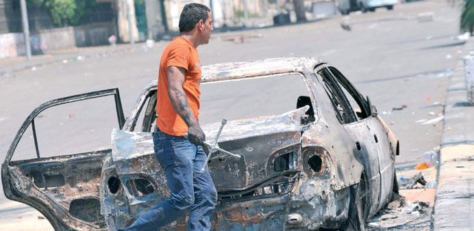  A man walks past a burnt car near Cairo University yesterday.