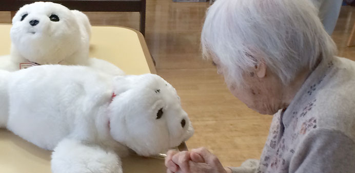 UP, CLOSE AND PERSONAL: A resident of the Fuyo-En rest home in Yokohama takes a closer look at Paro, a robot in the form of a toy white seal. 