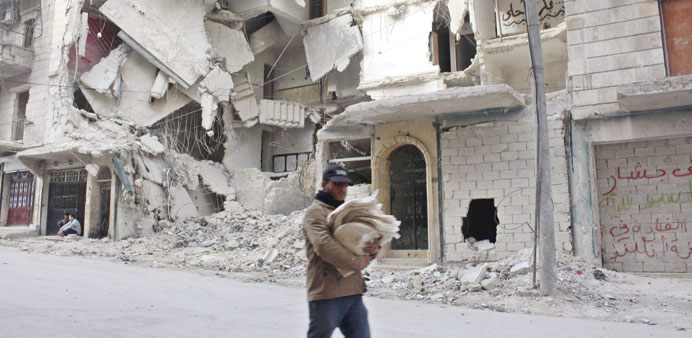 A man carries bread as he walks past damaged buildings in Aleppo yesterday.