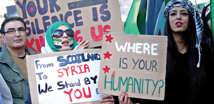 Anti-Syrian regime protesters hold placards and chant slogans during a rally outside Downing Street in London yesterday, to mark the third anniversary